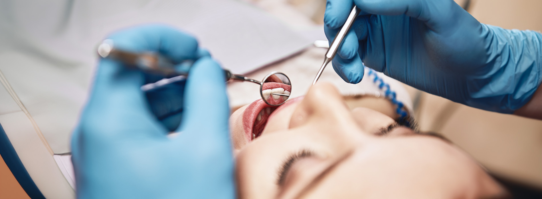 An image of a person receiving dental care with a dental professional performing a procedure using specialized tools.