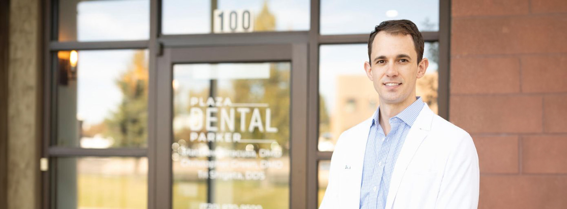 The image features a man standing outside a building with text indicating  Dental Clinic  and  100  Natural Teeth,  posing for a photo with a friendly expression.
