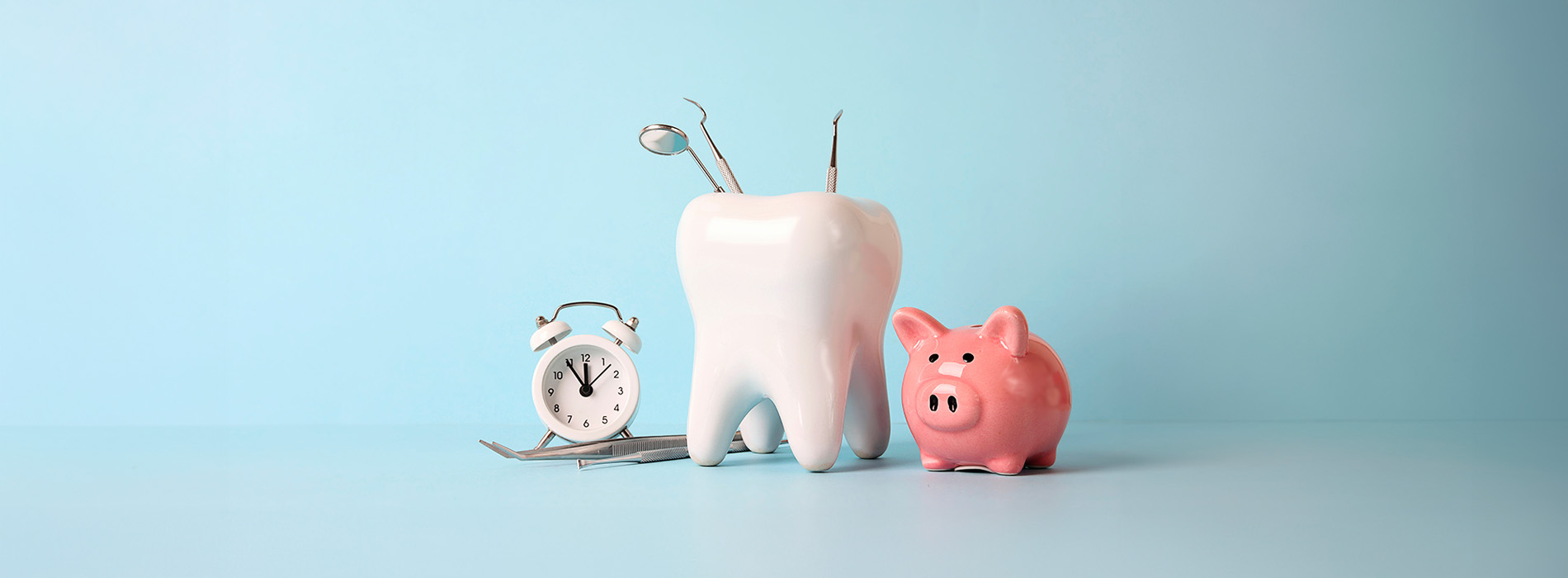 The image shows a piggy bank with a toothbrush placed inside it and a small toy figure next to it, set against a blue background.