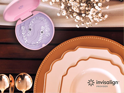 The image shows a close-up view of a dining table setting with various items including plates, bowls, and a tea set, with a focus on a purple toothbrush holder in the foreground.