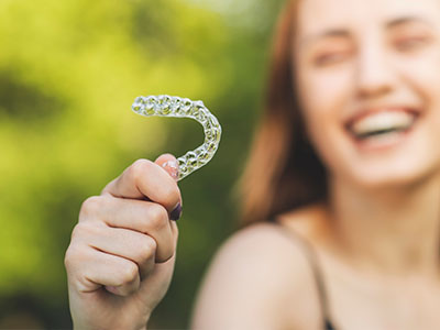 A young woman holding up a toothbrush with a smile on her face.