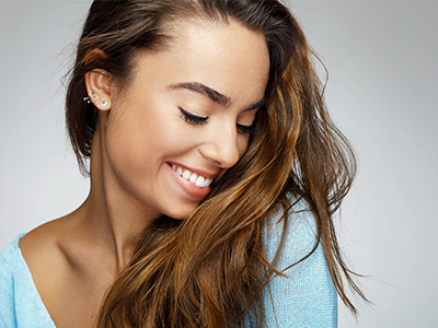 A woman with long hair smiling at the camera from two different angles.