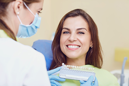 Woman receiving dental care with dental professional  dental chair, tools, and protective gear visible.