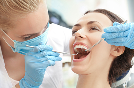 The image shows a dental professional performing oral care on a patient with visible teeth cleaning instruments and protective gloves.