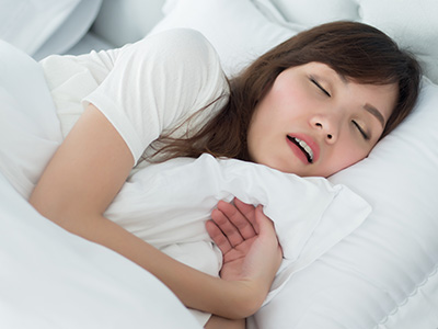 Woman asleep with eyes closed on bed.