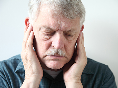 The image features a man with his hand on his ear, appearing to be in pain or distress, possibly due to an injury or illness.